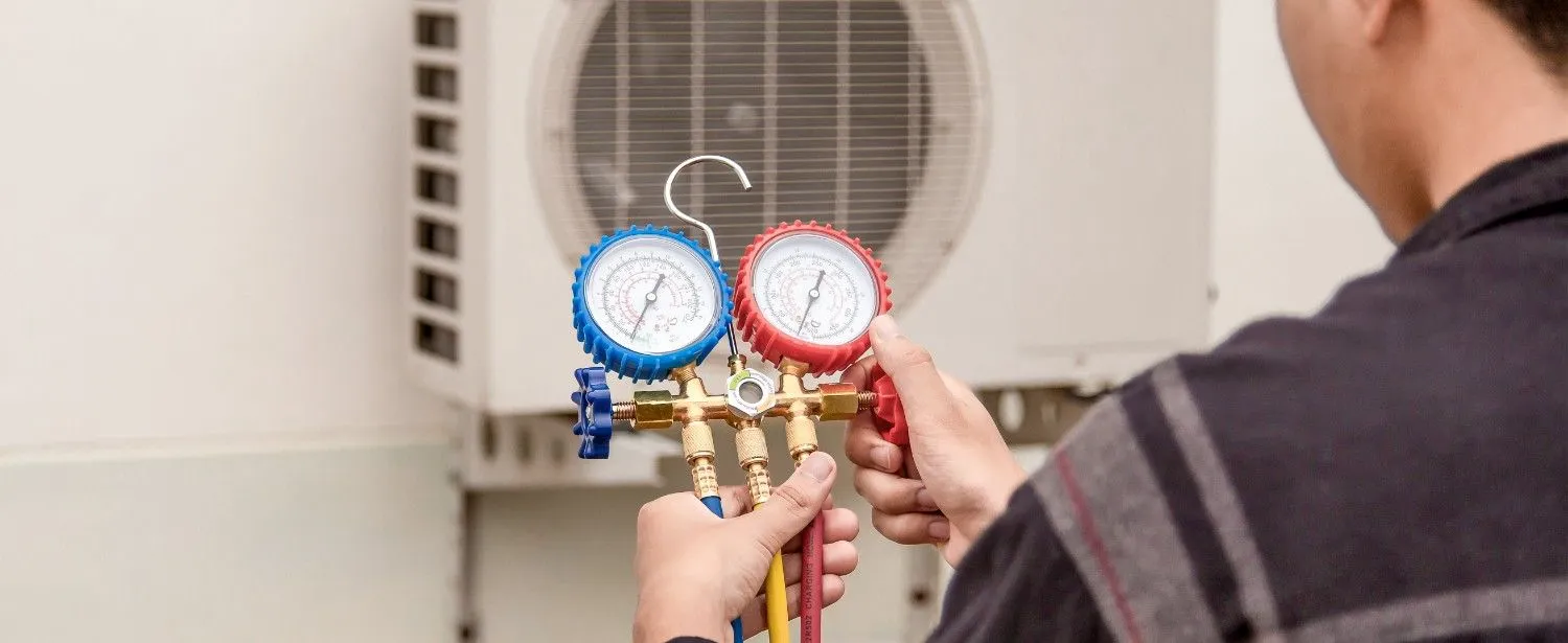 Technician checking an air conditioning unit with pressure gauges
